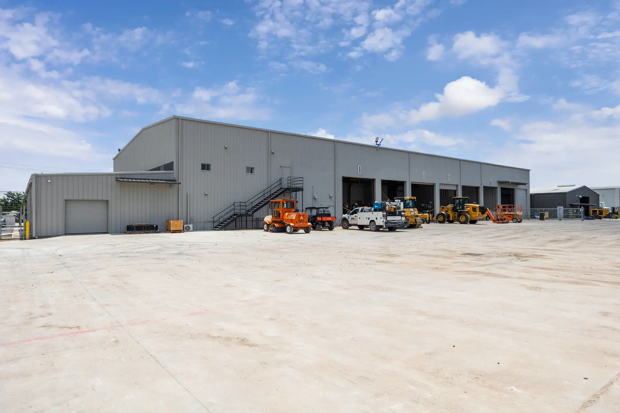 The service side of the building, bays open and equipment parked along the apron