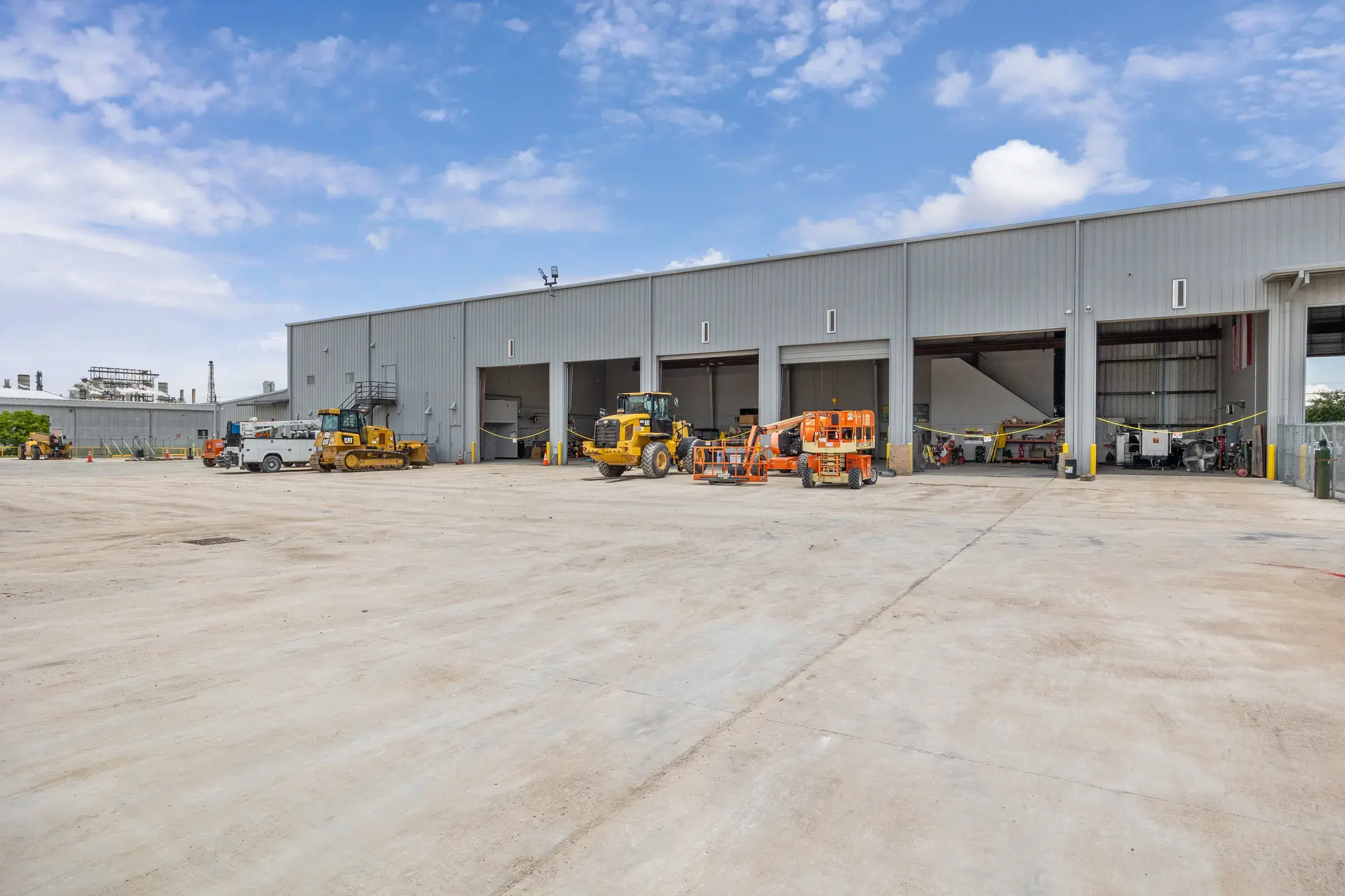 A run of service bays with wheel loaders and lifts parked across the concrete