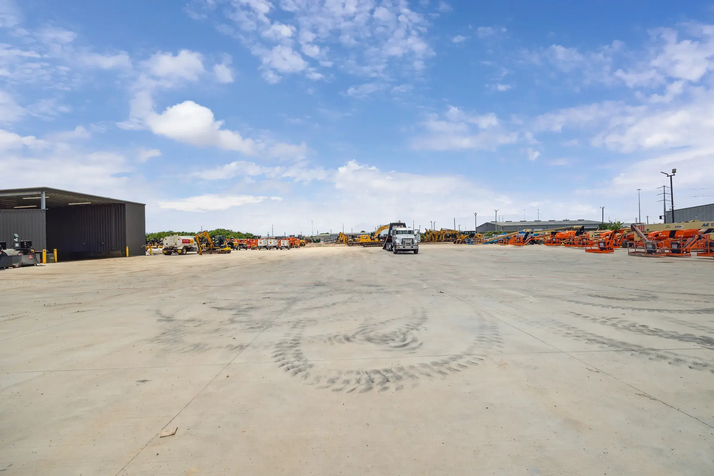 The open yard with equipment parked along the far fence line