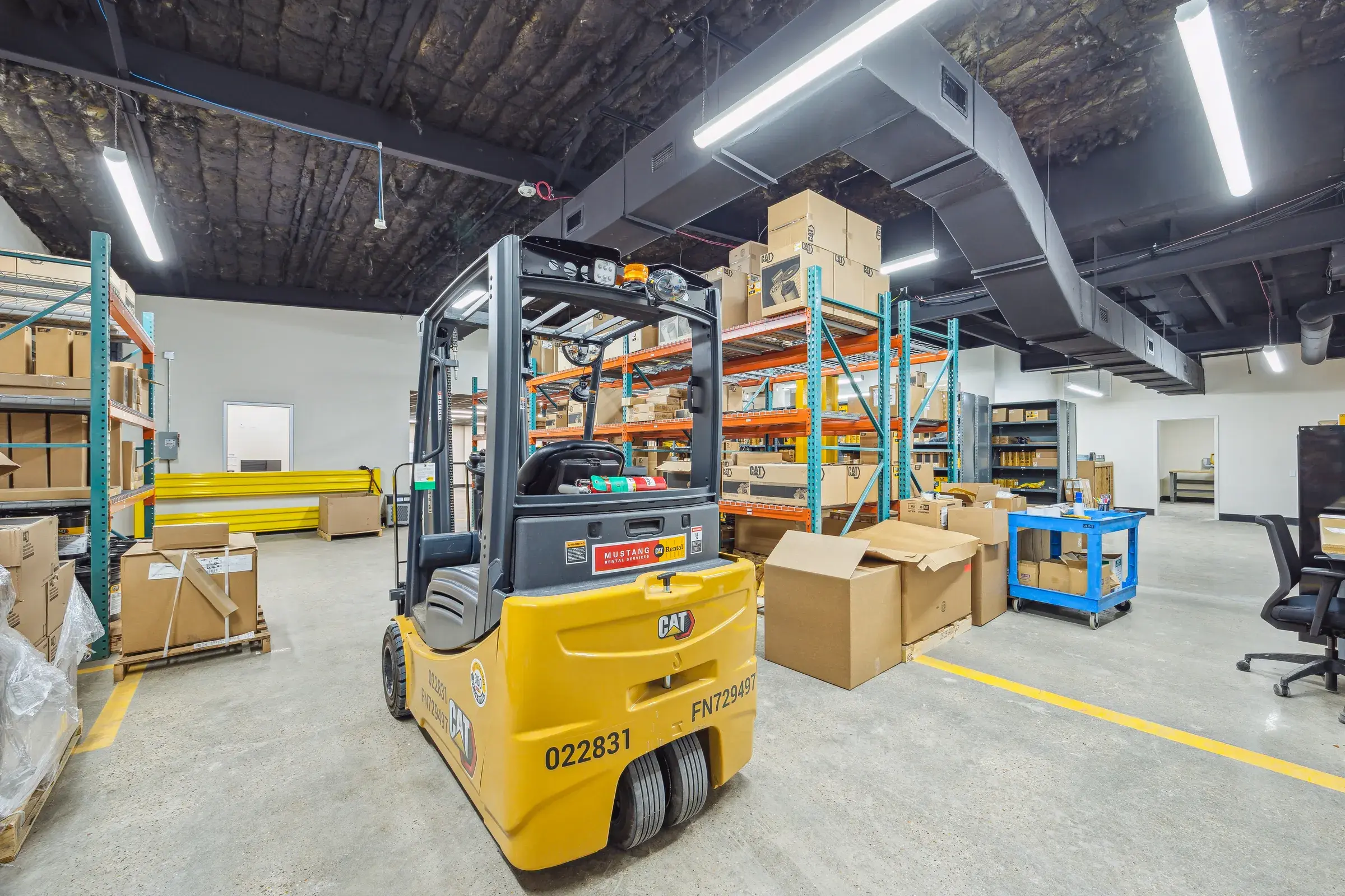 A forklift working the parts warehouse between the pallet racks