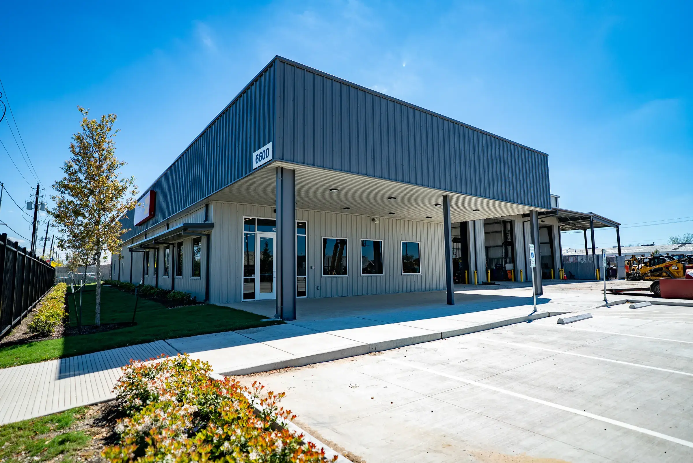 The completed Mustang CAT Long Drive facility — a long metal service building with a glazed entry and the branded canopy over the front doors