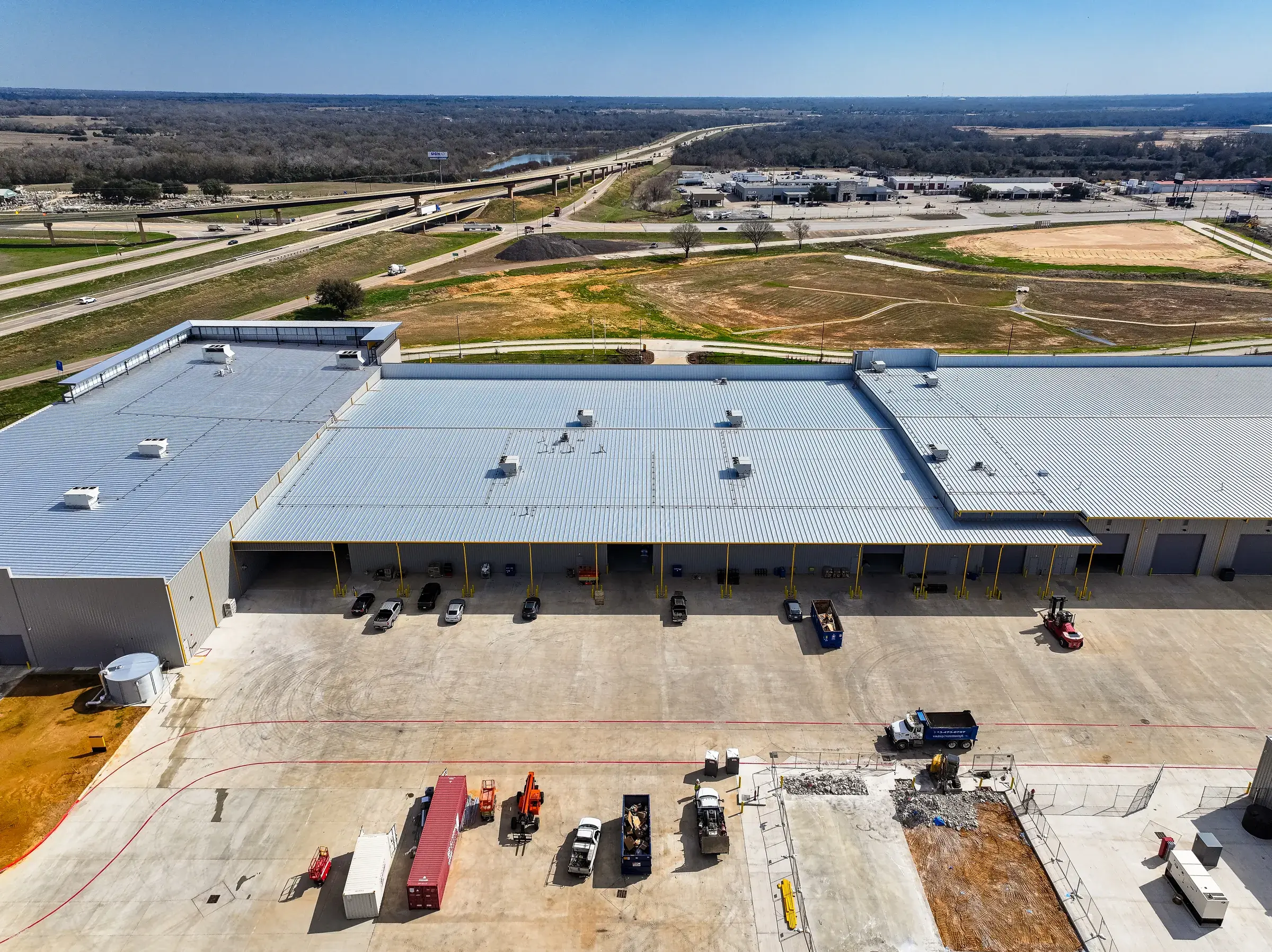 Aerial down the length of the service building, trailers backed in along the dock side