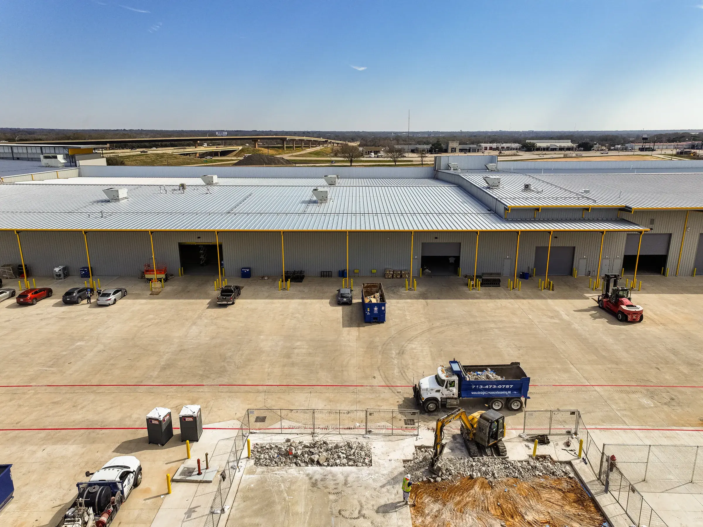 The yard alongside the shop with equipment and material staged across the concrete