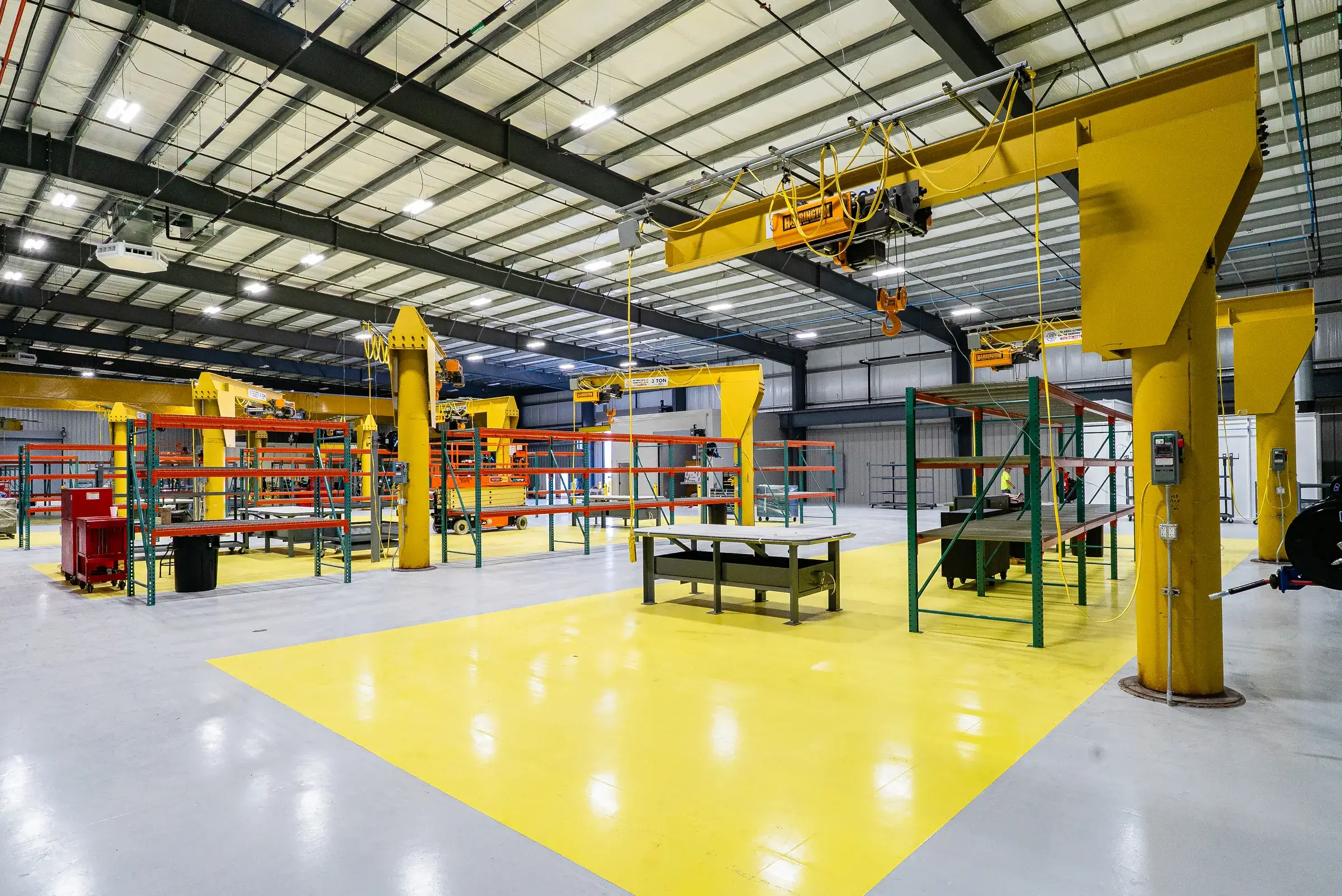 Jib cranes over the marked work zone with a fabrication bench set between them
