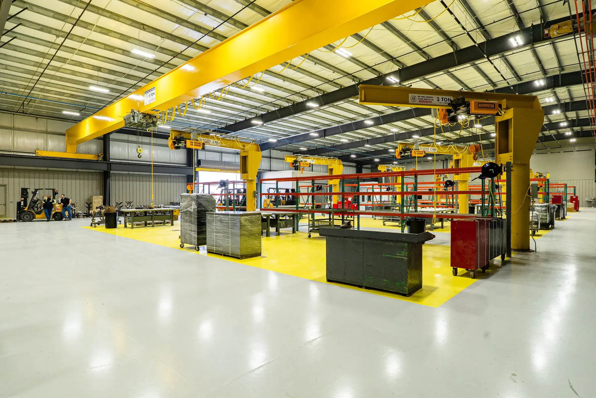 Overhead bridge crane running the length of the high-bay shop above workbenches and component racking