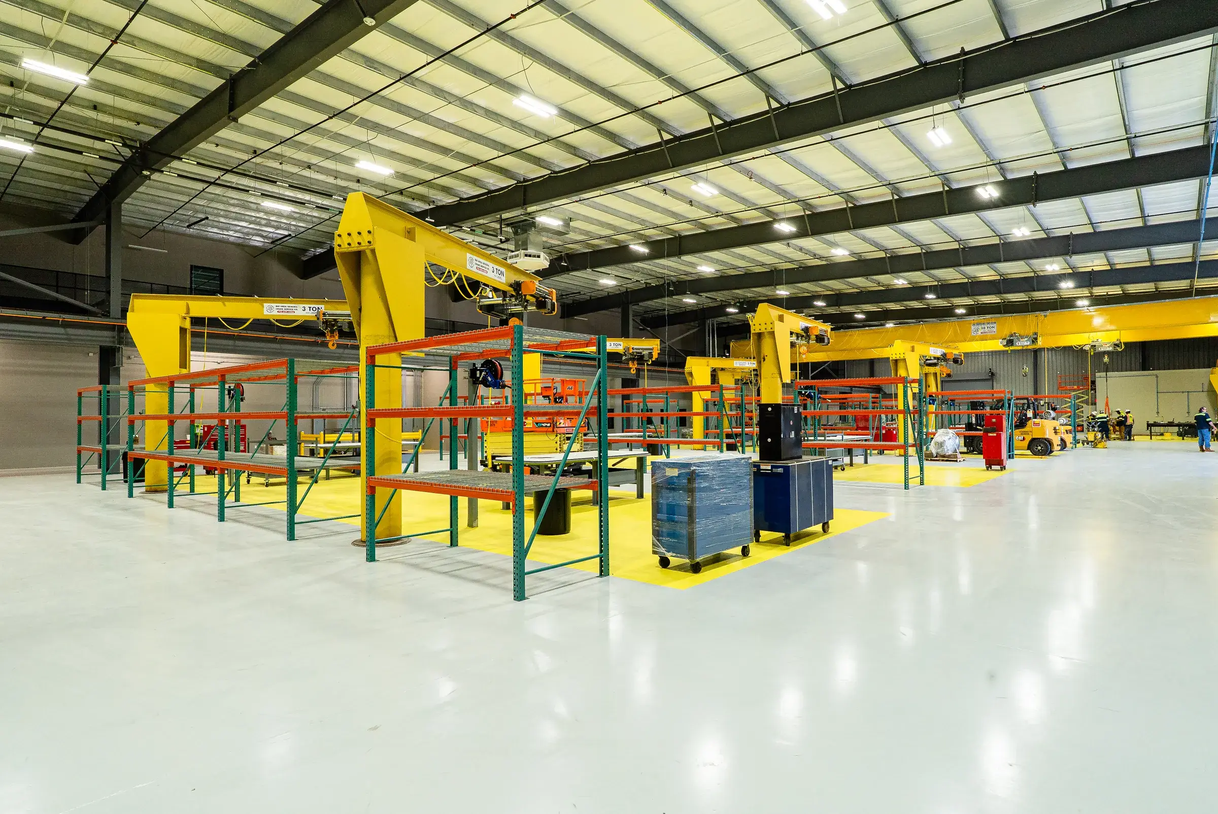 Wide view of the shop, benches and racking down both sides under the crane rail