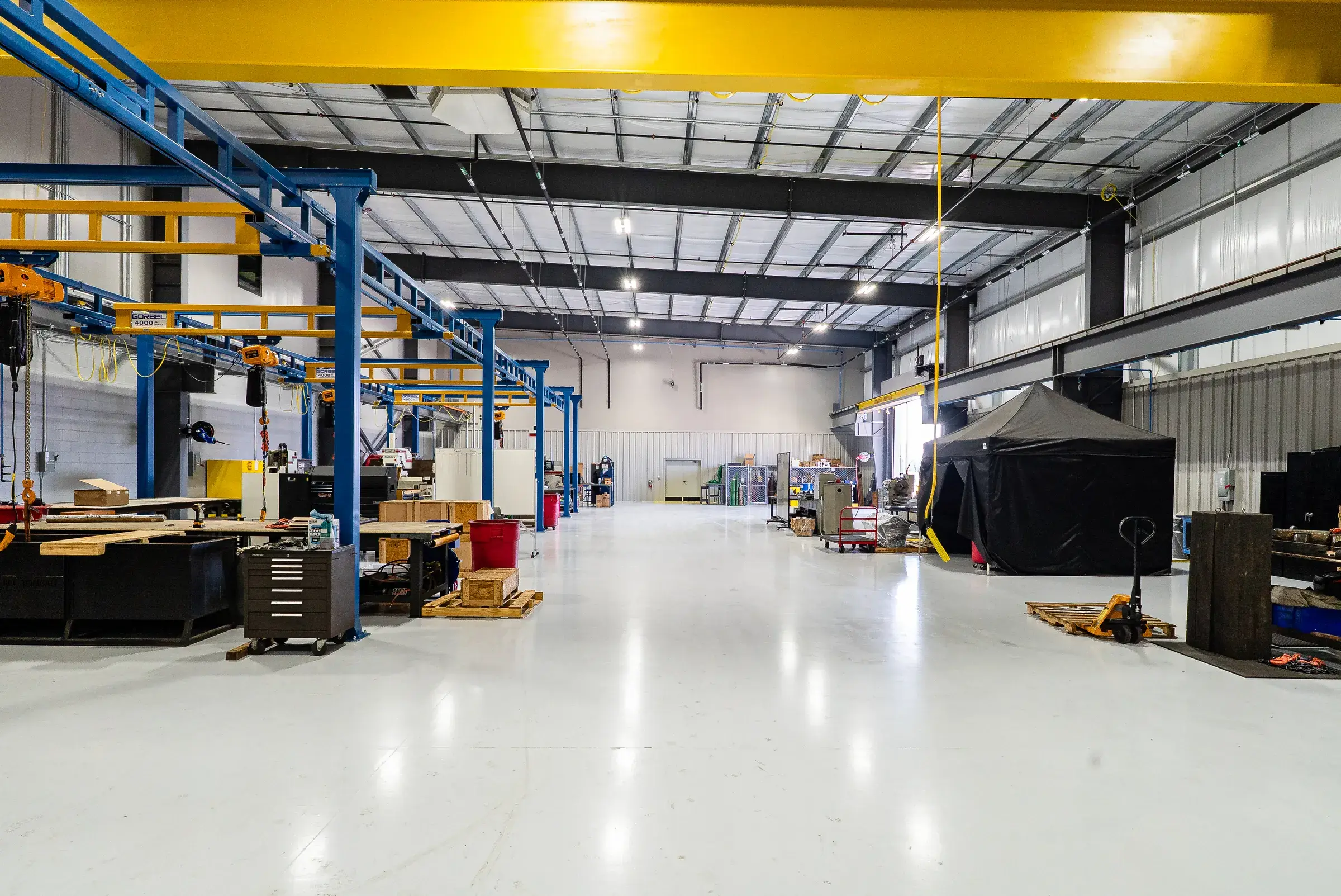 The blue and yellow crane bays with equipment and tooling staged along the floor