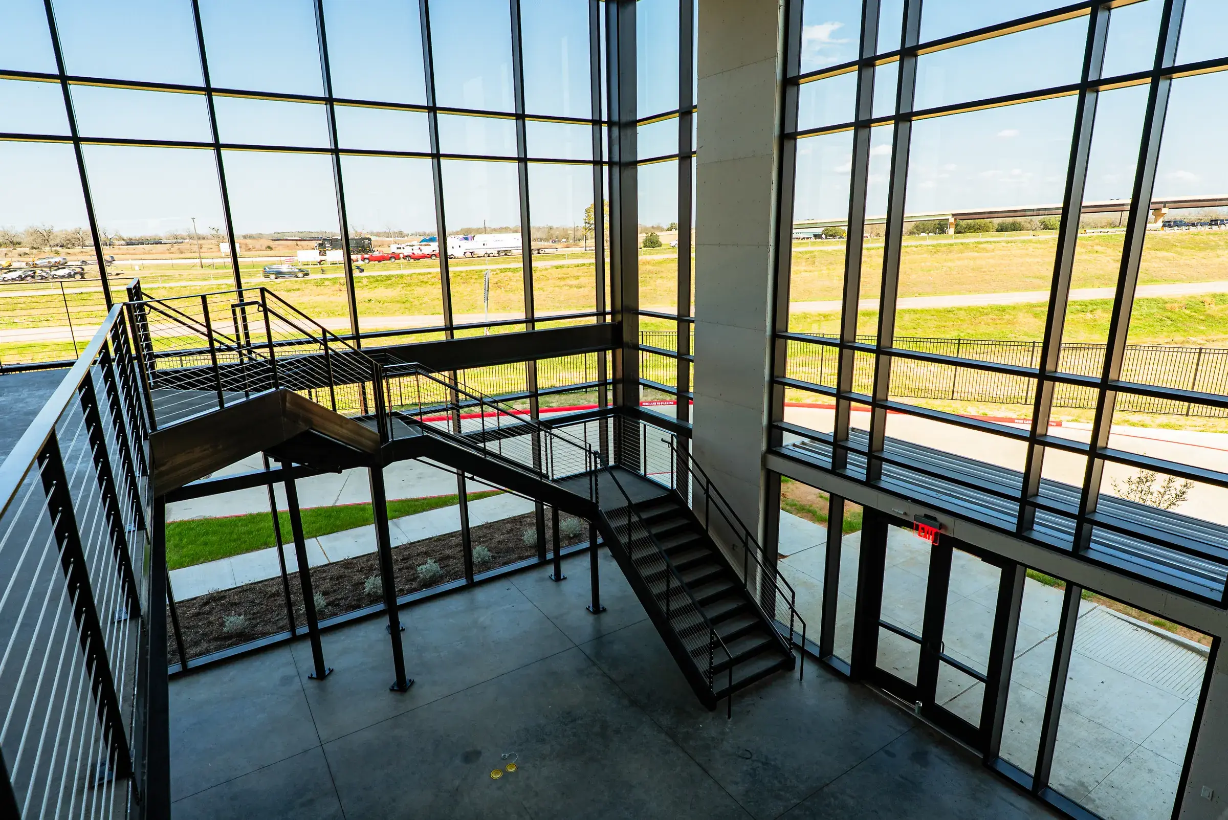 The glazed stair connecting the office levels, steel stair set against a full-height window wall
