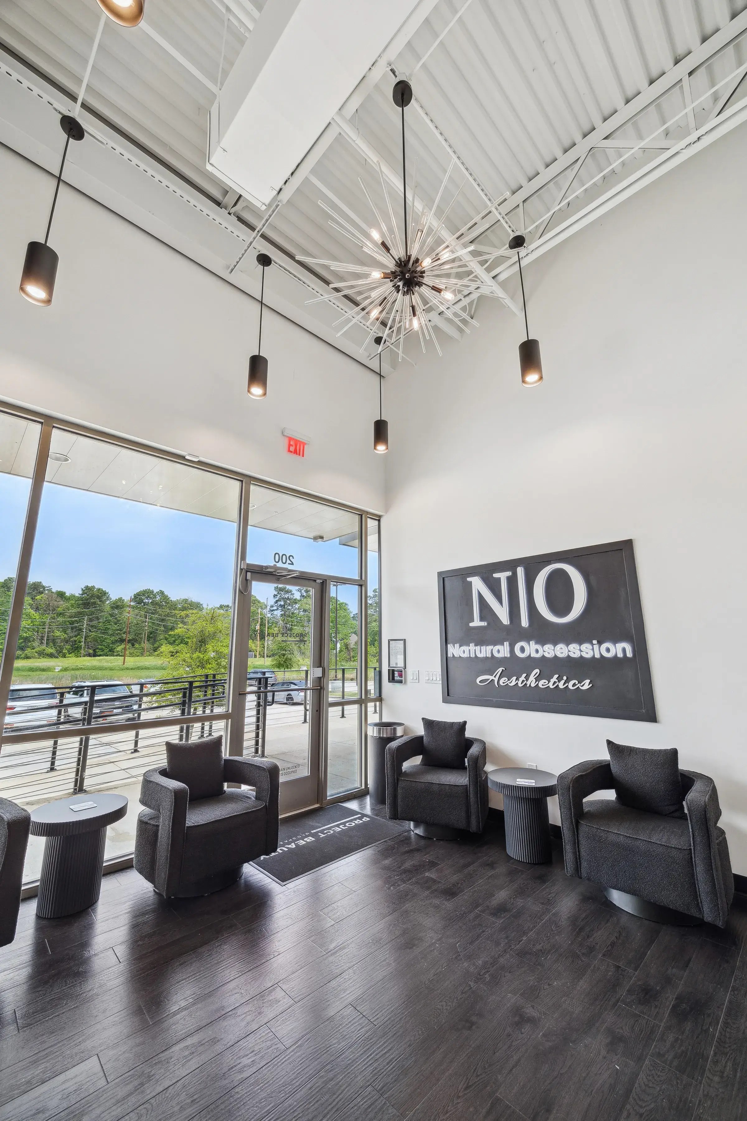 The double-height lounge and waiting area under sputnik chandeliers, tenant signage on the far wall