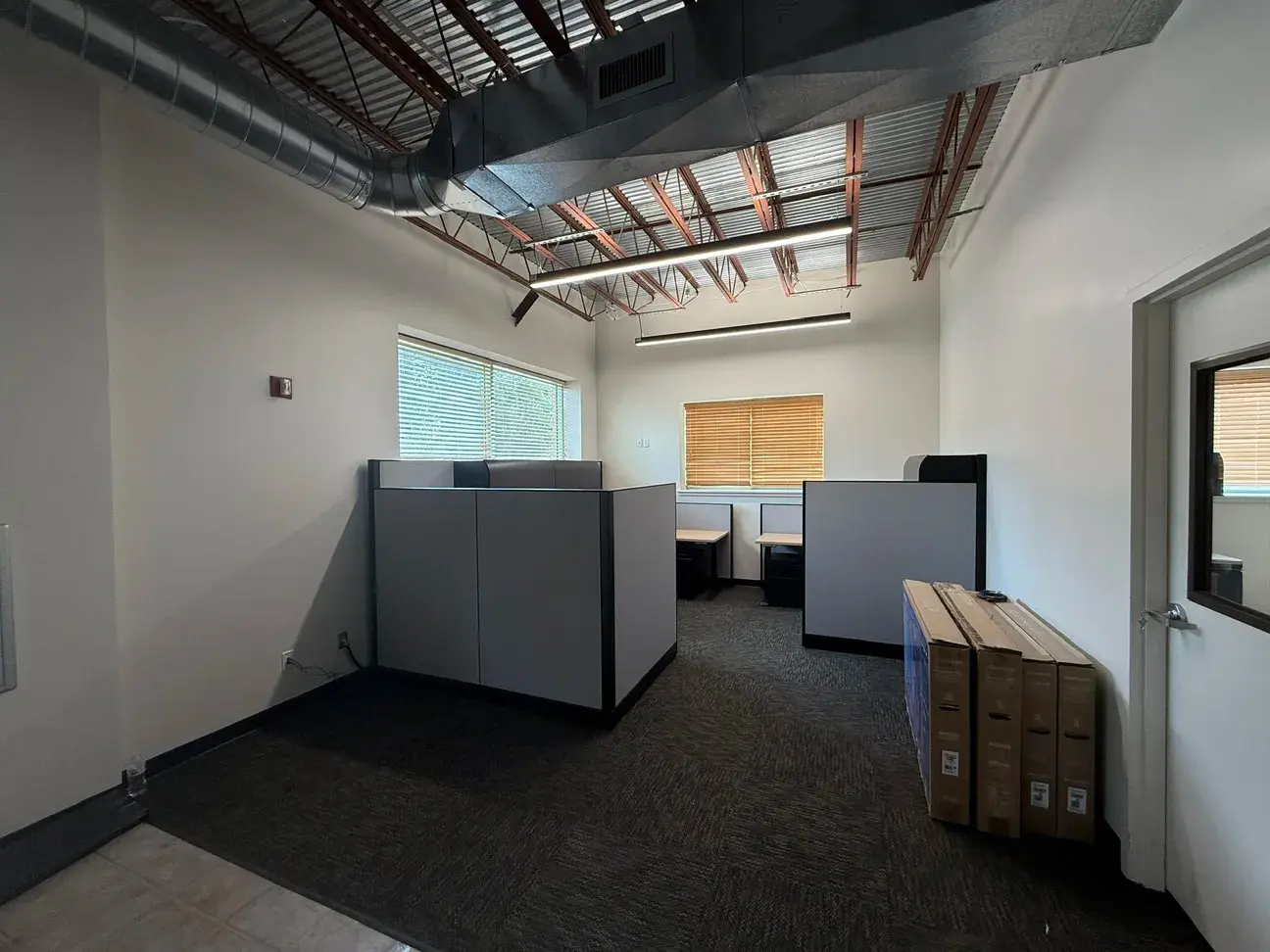 A carpeted office area with workstations set against a window wall, opening off the tiled main floor